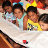 Children watch on with glee as a small toy train makes its way across a paper bridge that is stretched across their arms during last
week's Vacation Bible School at the Carnegie Church of the Nazarene. In all, about 70 youngsters attended the week-long event.
